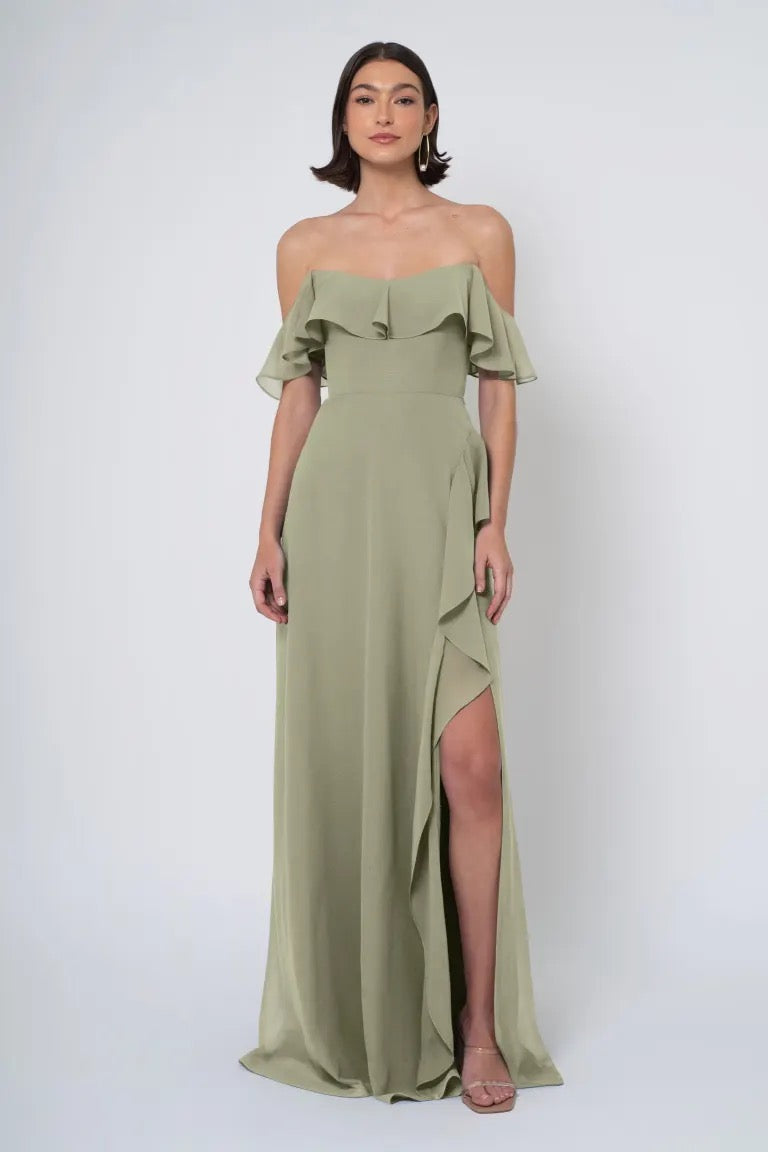 Woman in an olive green off-the-shoulder neckline Salma gown by Jenny Yoo Bridesmaid Dress with a side slit from Bergamot Bridal.