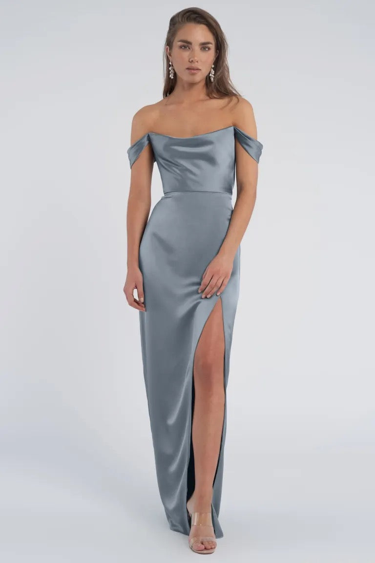 Woman posing in a luxe satin, off-the-shoulder silver gown with a thigh-high slit - Sawyer Bridesmaid Dress by Jenny Yoo for Bergamot Bridal.