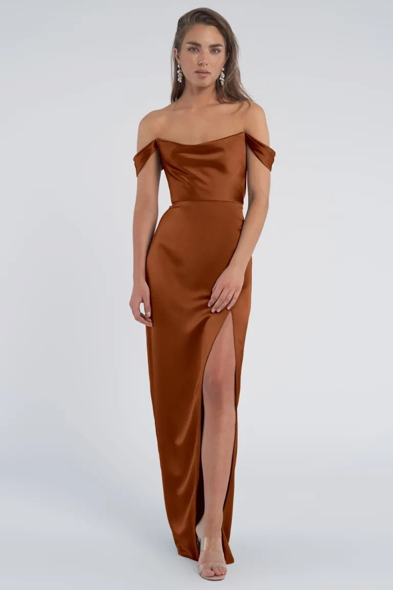 Woman in a Sawyer - Bridesmaid Dress by Jenny Yoo in luxe satin, off-shoulder brown dress with a thigh-high slit from Bergamot Bridal.