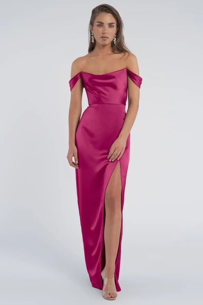 Woman in a luxe satin off-the-shoulder magenta Sawyer - Bridesmaid Dress by Jenny Yoo gown with a thigh-high slit from Bergamot Bridal.