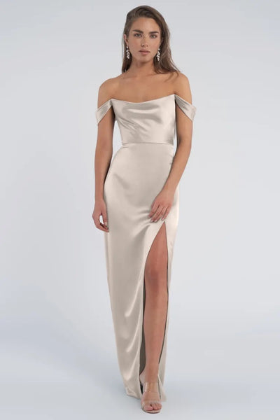 A woman in an elegant draped off-the-shoulder Sawyer bridesmaid dress by Jenny Yoo with a thigh-high slit from Bergamot Bridal.
