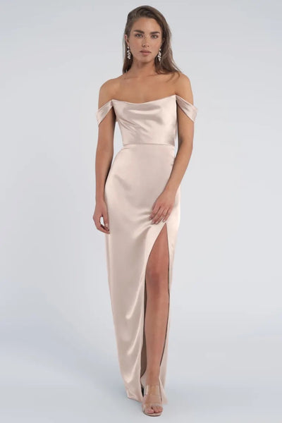Woman wearing a Sawyer bridesmaid dress by Jenny Yoo from Bergamot Bridal, a luxe satin evening gown with off-the-shoulder sleeves and a thigh-high slit.