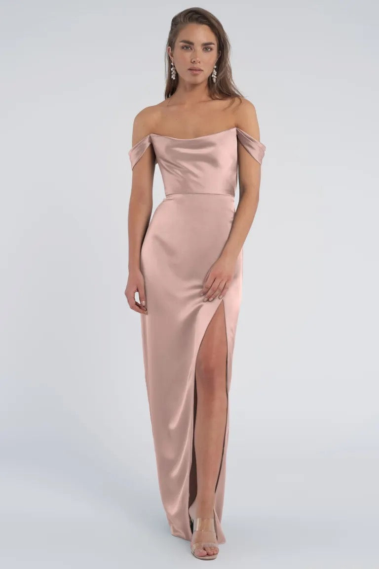 Woman posing in an elegant off-the-shoulder sleeves, luxe satin Sawyer - Bridesmaid Dress by Jenny Yoo with a thigh-high slit from Bergamot Bridal.