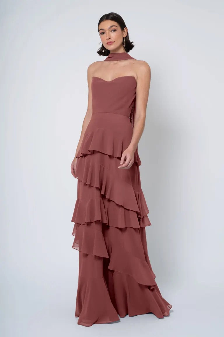 Woman posing in a Simona - Jenny Yoo Bridesmaid Dress from Bergamot Bridal, which features a strapless cowl neckline and ruffled skirt.