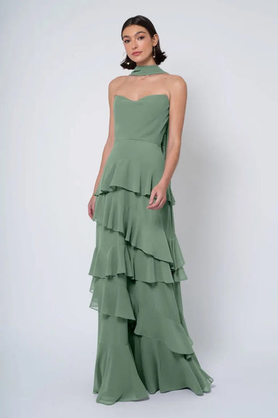 A woman in an elegant green strapless cowl neckline Simona - Jenny Yoo Bridesmaid Dress stands against a white background.