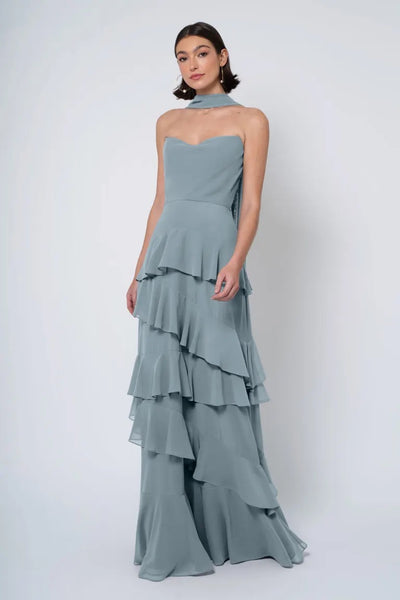 A woman in an elegant, Jennifer Yoo chiffon bridesmaid dress with a strapless cowl neckline posing against a white background.