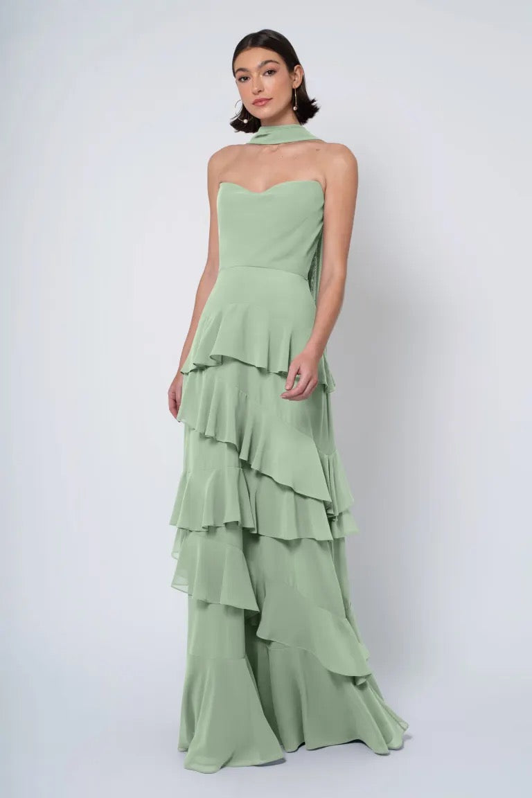 A woman in a strapless cowl neckline, light green Jenny Yoo Bridesmaid Dress posing against a white background.