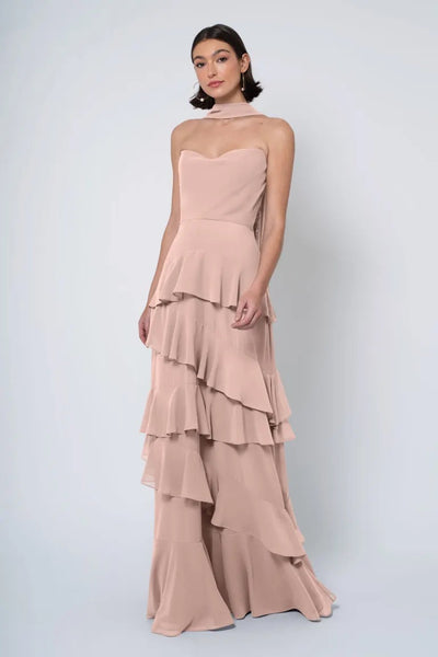 Woman posing in a layered, strapless cowl neckline blush Simona gown by Jenny Yoo at Bergamot Bridal.