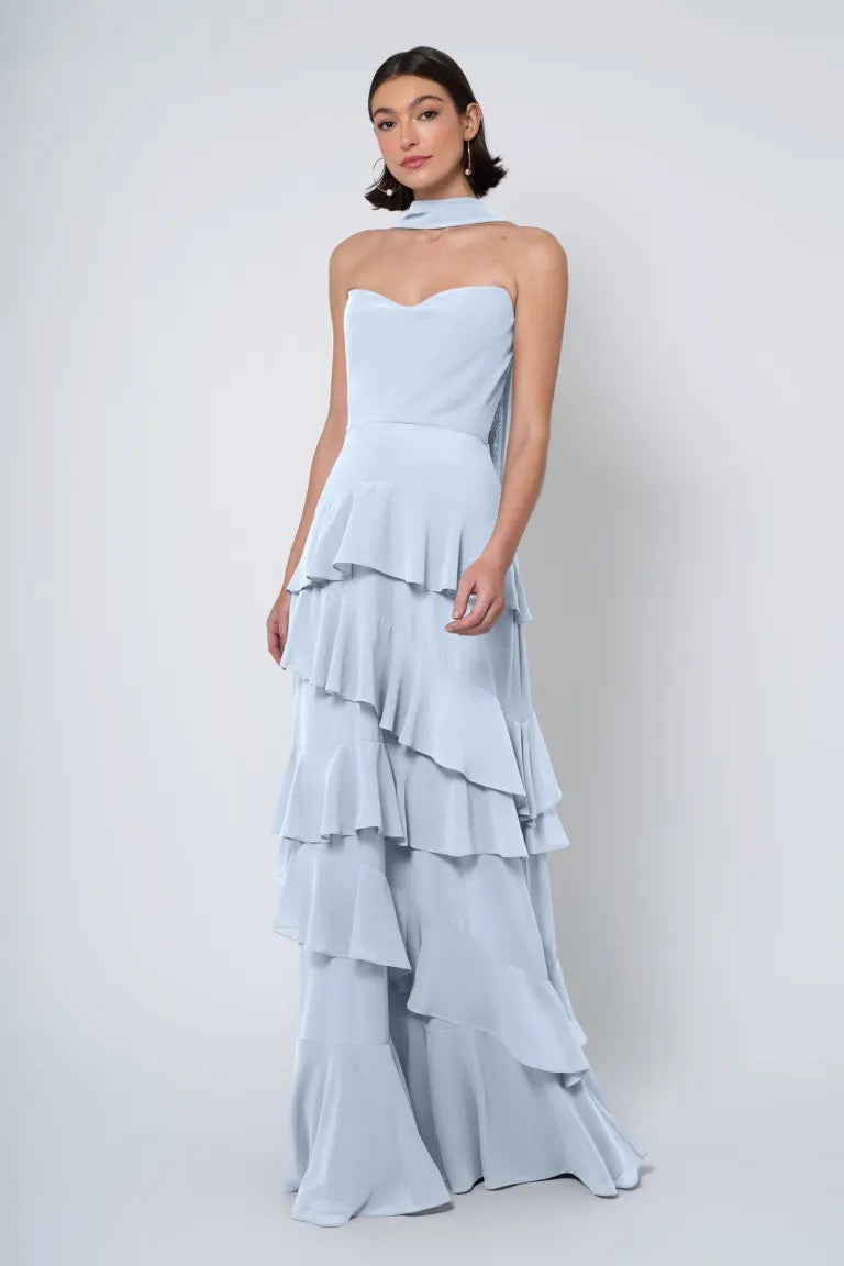 A woman poses in a strapless cowl neckline light blue tiered dress with ruffled skirt, the Simona Jenny Yoo Bridesmaid Dress from Bergamot Bridal.