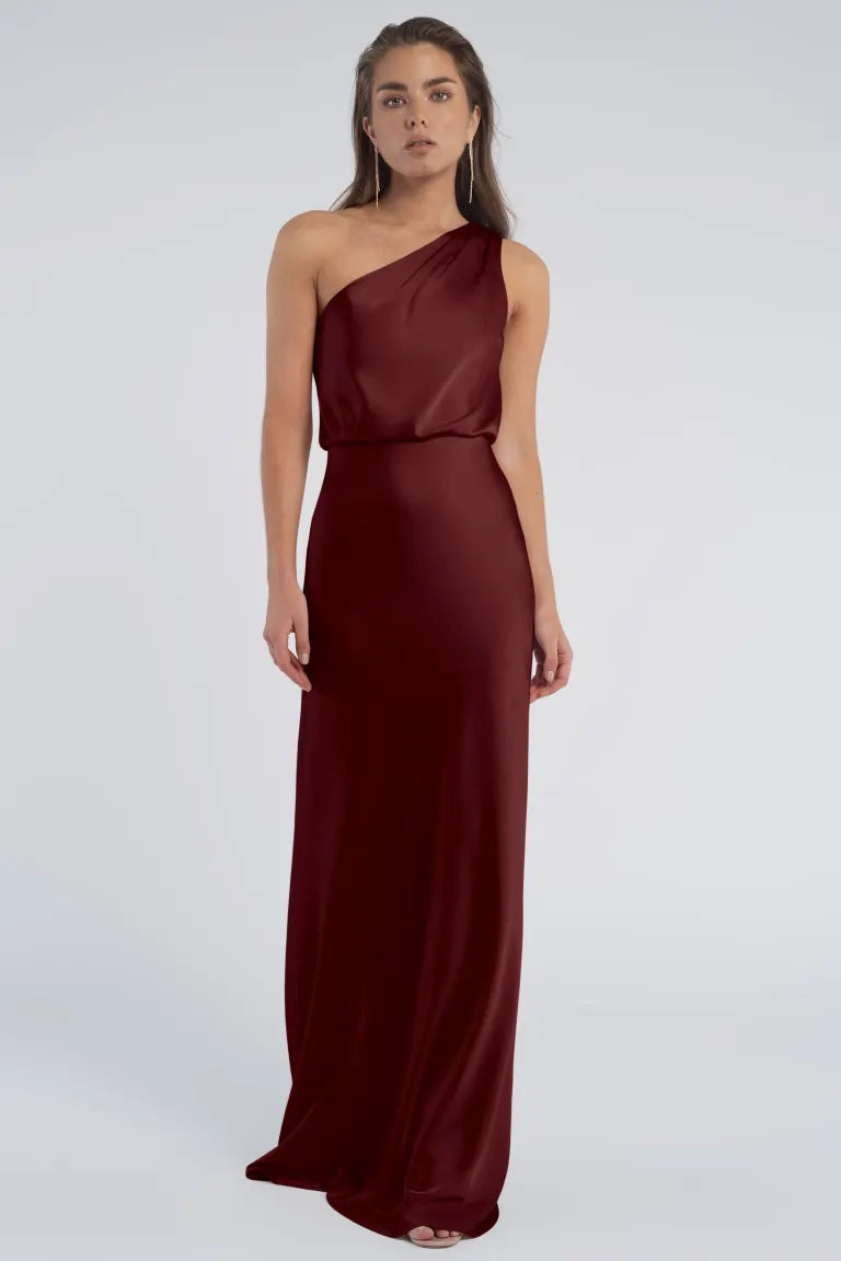 Woman in a one-shoulder neckline Sterling - Jenny Yoo Bridesmaid evening gown standing against a neutral background from Bergamot Bridal.