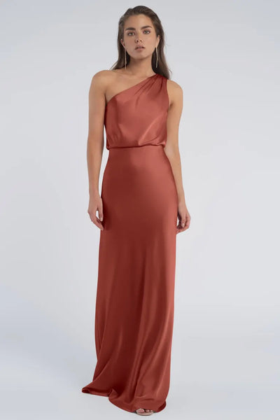 A woman in an elegant red Jenny Yoo Bridesmaid dress with a one-shoulder neckline from Bergamot Bridal.
