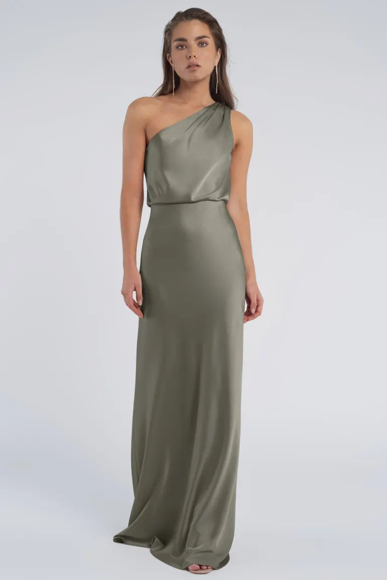 A woman in an elegant, one-shoulder neckline, olive green evening gown crafted from luxe satin fabric by Sterling - Jenny Yoo Bridesmaid from Bergamot Bridal.