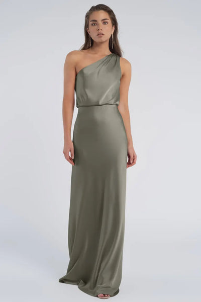 A woman in an elegant, one-shoulder neckline, olive green evening gown crafted from luxe satin fabric by Sterling - Jenny Yoo Bridesmaid from Bergamot Bridal.