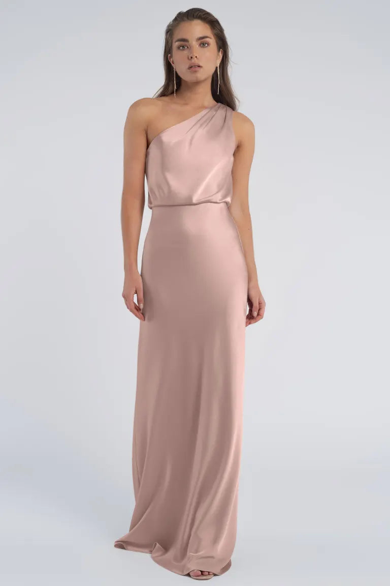 Woman in a Jenny Yoo Bridesmaid dress with a one-shoulder neckline standing against a grey background.