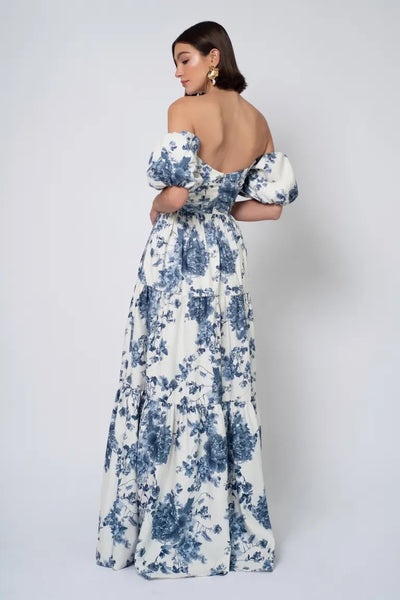 A woman posing in an elegant Jenny Yoo Bridesmaid Dress with detachable puff sleeves and a blue floral pattern from Bergamot Bridal.