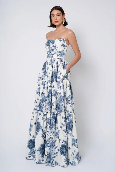 Woman posing in a strapless white Jenny Yoo Bridesmaid Dress with blue floral print and detachable puff sleeves from Bergamot Bridal.