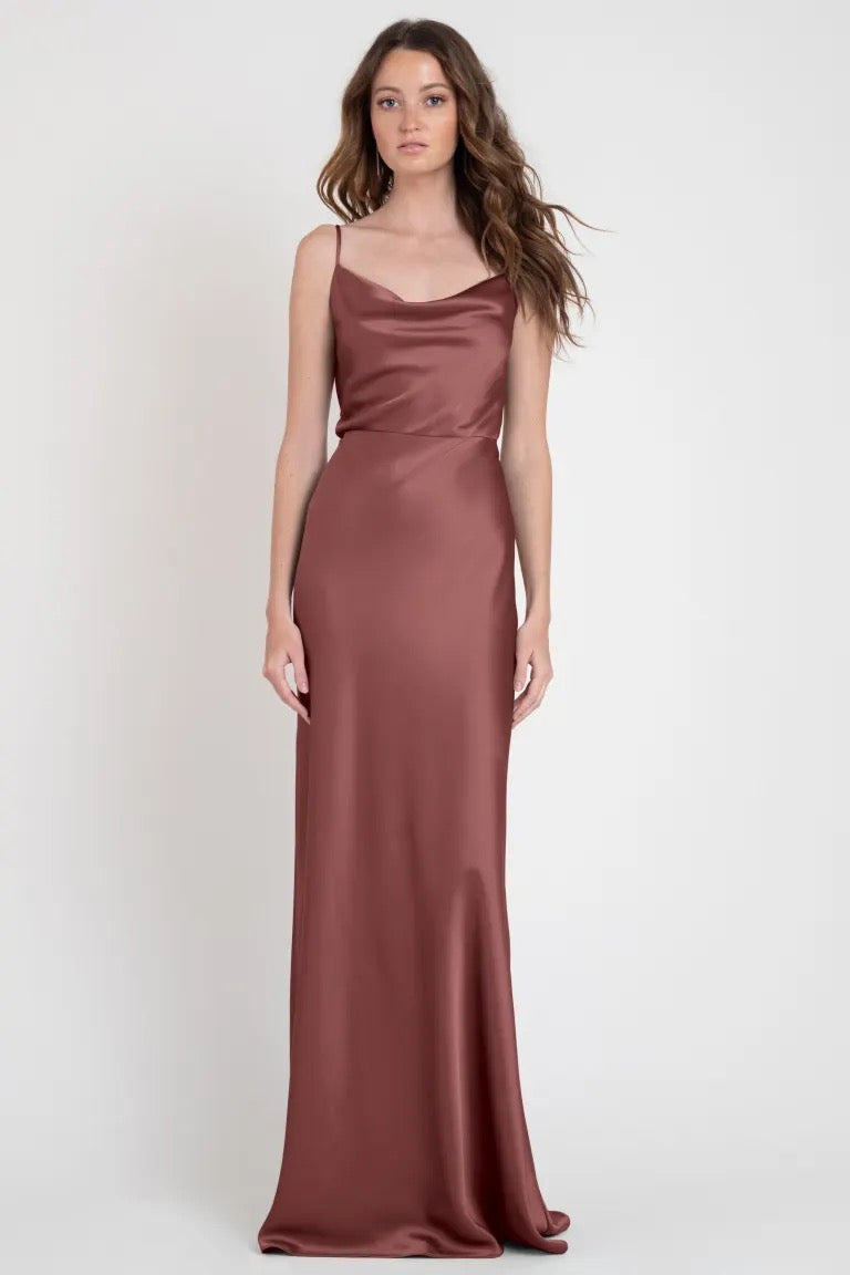 A woman modeling a stylish, long Sylvie - Bridesmaid Dress by Jenny Yoo in a solid muted color, evoking Old Hollywood elegance from Bergamot Bridal.