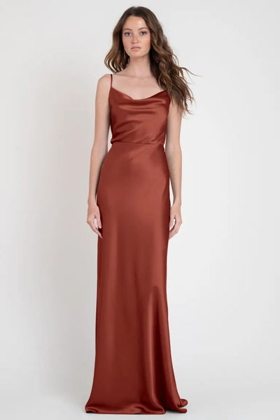 Woman in a long, sleeveless Sylvie - Bridesmaid Dress by Jenny Yoo standing against a neutral background, giving off Old Hollywood vibes from Bergamot Bridal.