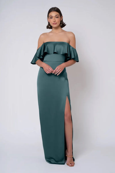 A woman posing in an elegant Winter - Jenny Yoo Bridesmaid Dress gown with a slit from Bergamot Bridal.