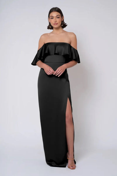 A woman posing in a strapless, black off-the-shoulder gown with a side slit by Bergamot Bridal's Winter - Jenny Yoo Bridesmaid Dress.