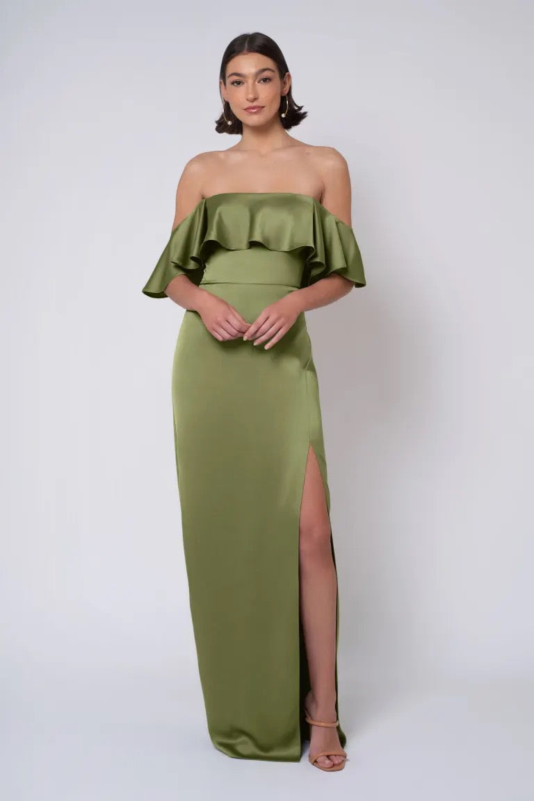 A woman in a Winter - Jenny Yoo Bridesmaid Dress from Bergamot Bridal, featuring a green strapless neckline gown with a thigh-high slit, is posing against a white background.