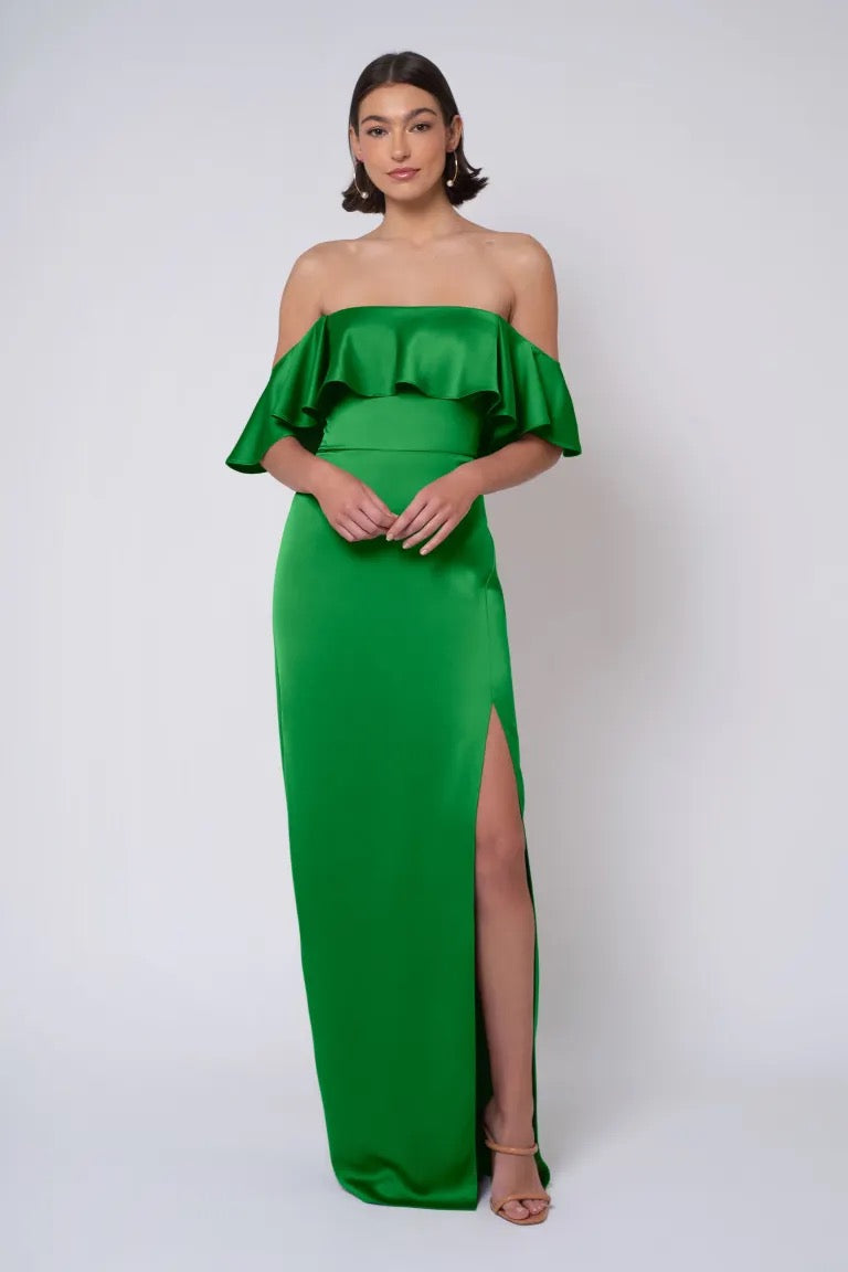 A woman in a green strapless Jenny Yoo Bridesmaid Dress from Bergamot Bridal with a thigh-high slit.