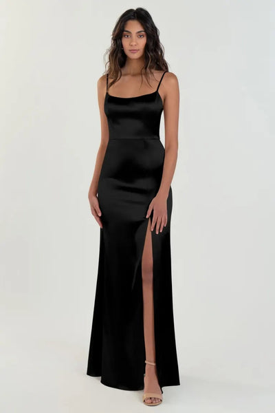 A woman modeling a Chase - Bridesmaid Dress by Jenny Yoo in black satin back crepe, featuring a thigh-high slit from Bergamot Bridal.