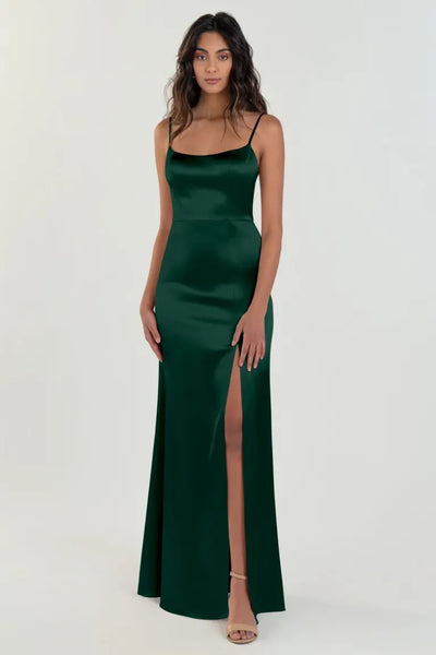 Woman posing in an elegant green Chase bridesmaid dress by Jenny Yoo, featuring a scoop neck and satin back crepe, with a high slit from Bergamot Bridal.