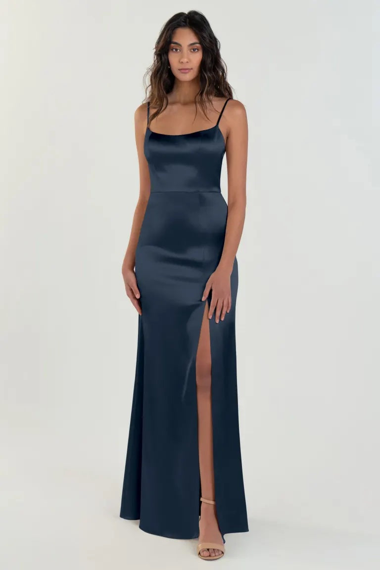 A woman wearing a Chase bridesmaid dress by Jenny Yoo in navy blue satin back crepe with a thigh-high slit and scoop neck from Bergamot Bridal.