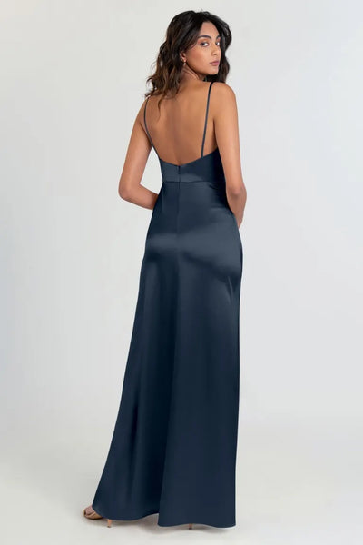 A woman posing in an elegant navy blue Jenny Yoo Chase bridesmaid dress with a scoop neck and a satin back crepe from Bergamot Bridal.