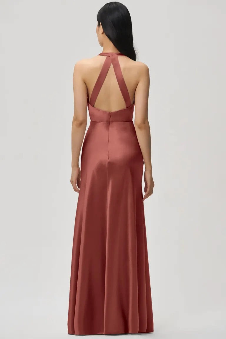 Woman wearing an elegant backless red satin Corinne - Bridesmaid Dress by Jenny Yoo with a criss-cross strap design from Bergamot Bridal.