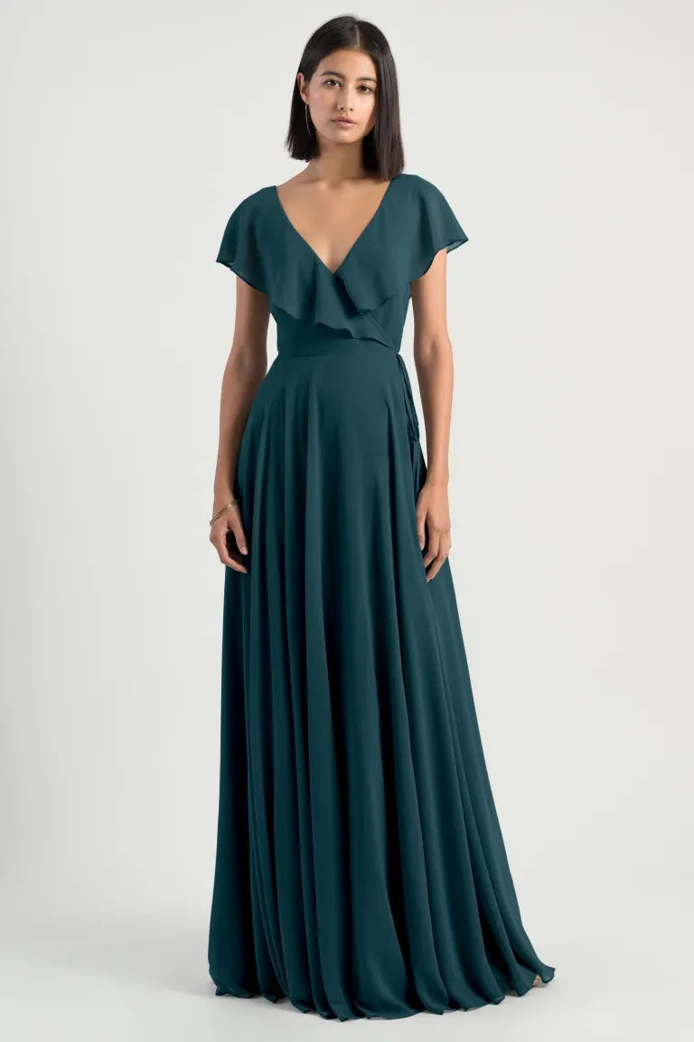 Woman posing in an elegant teal chiffon Faye - Bridesmaid Dress by Jenny Yoo with a v-neckline and adjustable waist from Bergamot Bridal.