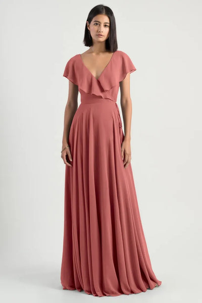 Woman in an elegant rose-colored flutter sleeve v-neck Faye bridesmaid dress by Jenny Yoo with an adjustable waist from Bergamot Bridal.