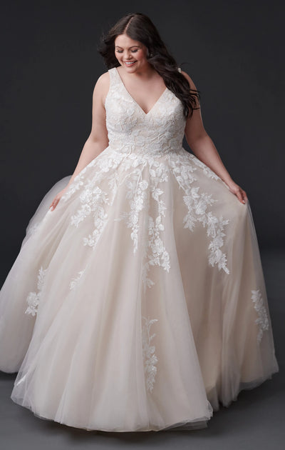 Woman in an elegant plus-size Eddy K Geneva - Off The Rack wedding dress with lace detailing and floral appliqués from Bergamot Bridal.