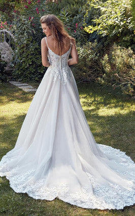A woman in a white Bergamot Bridal Eddy K Daphne - Off The Rack tulle gown with lace details standing in a garden.