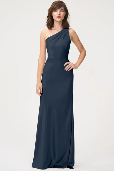 Woman in an elegant Lena - Bridesmaid Dress by Jenny Yoo featuring a one-shoulder neckline, crafted from navy blue satin back crepe at Bergamot Bridal.