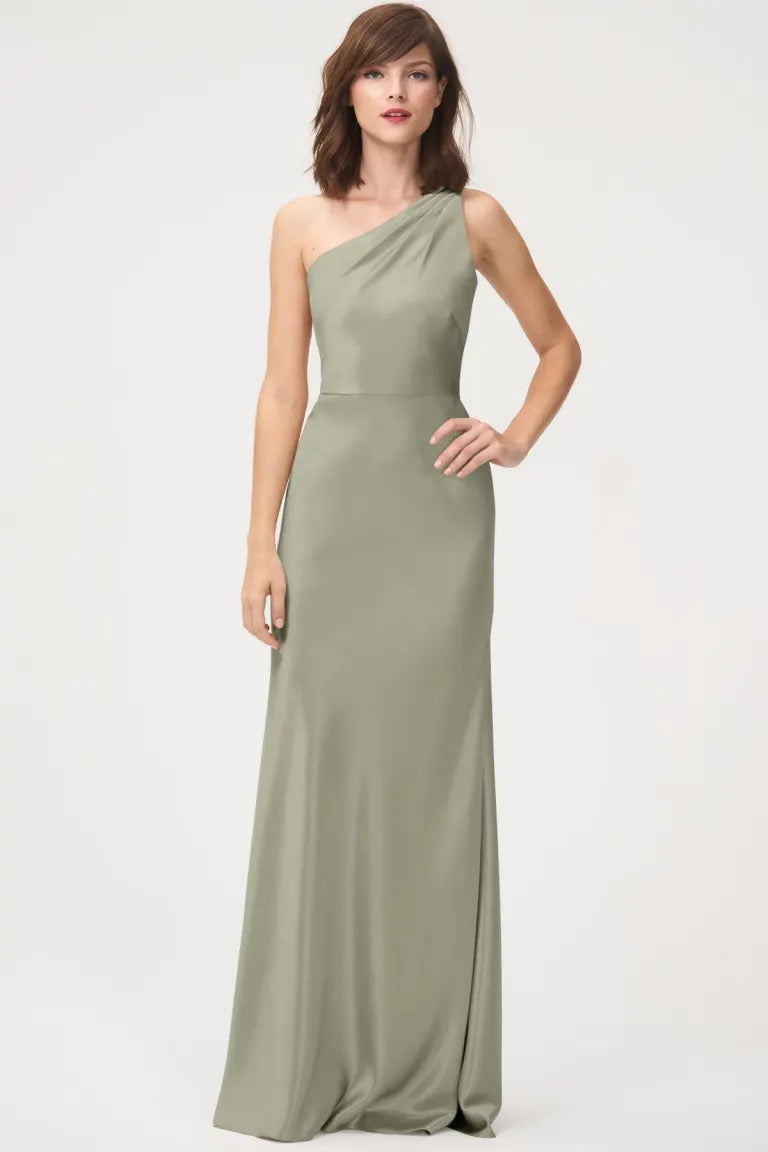 Woman posing in a one-shoulder neckline Lena Bridesmaid Dress by Jenny Yoo crafted from satin back crepe, in sage green, available at Bergamot Bridal.