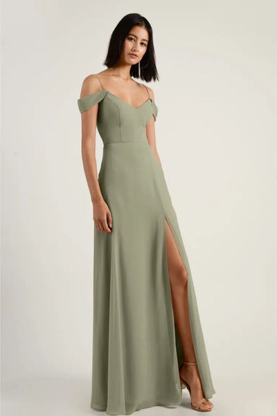 A woman models a floor-length olive green chiffon bridesmaid dress with a Jenny Yoo V-neck, thigh-high slit, and off-the-shoulder straps at Bergamot Bridal.