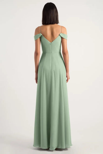 Woman in a pastel green, Priya V-neck chiffon bridesmaid dress by Jenny Yoo with an A-line skirt and off-the-shoulder sleeves, viewed from the back.