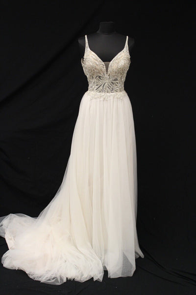 A long white A-line wedding dress with a beaded bodice and a flowing English net skirt, displayed on a mannequin against a black backdrop, the Bergamot Bridal Justin Alexander Cady Dress - Off The Rack.