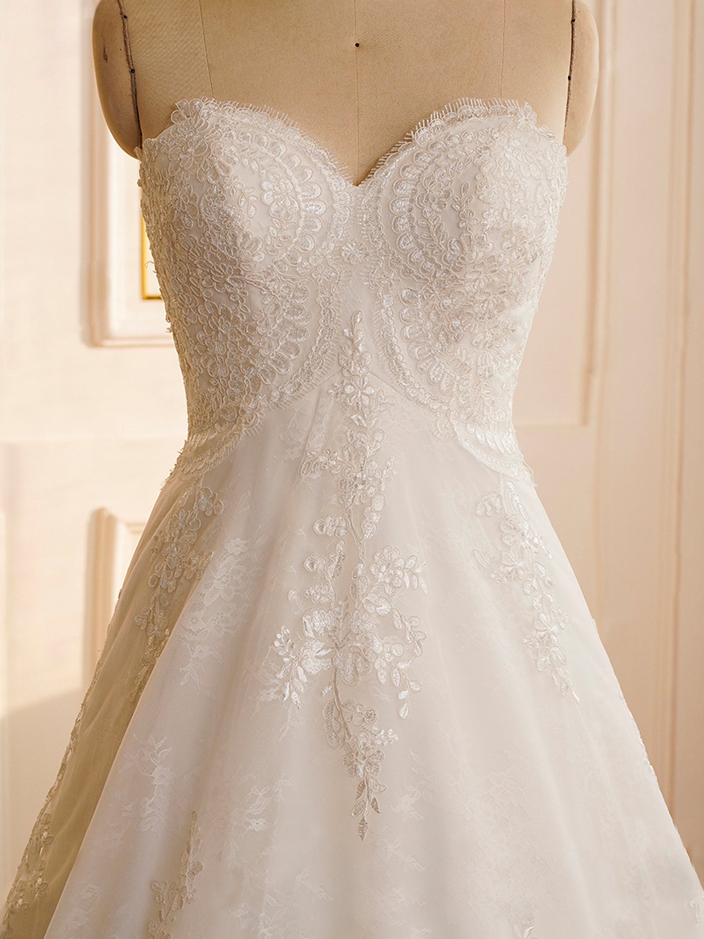 A Bergamot Bridal Strapless Whole Lace Court Train Wedding Dress in a bridal shop in London.