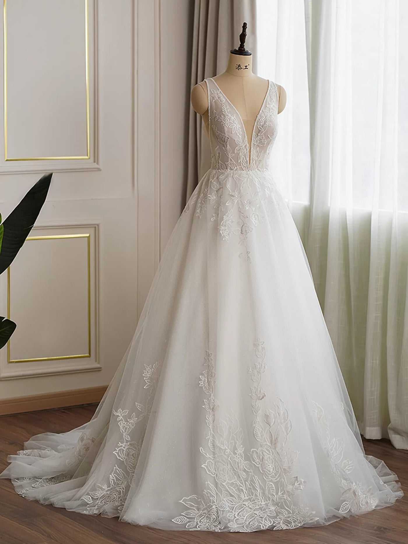 A Plunging V Neckline Lace Ball Gown Bridal Dress in a Bergamot Bridal shop window.