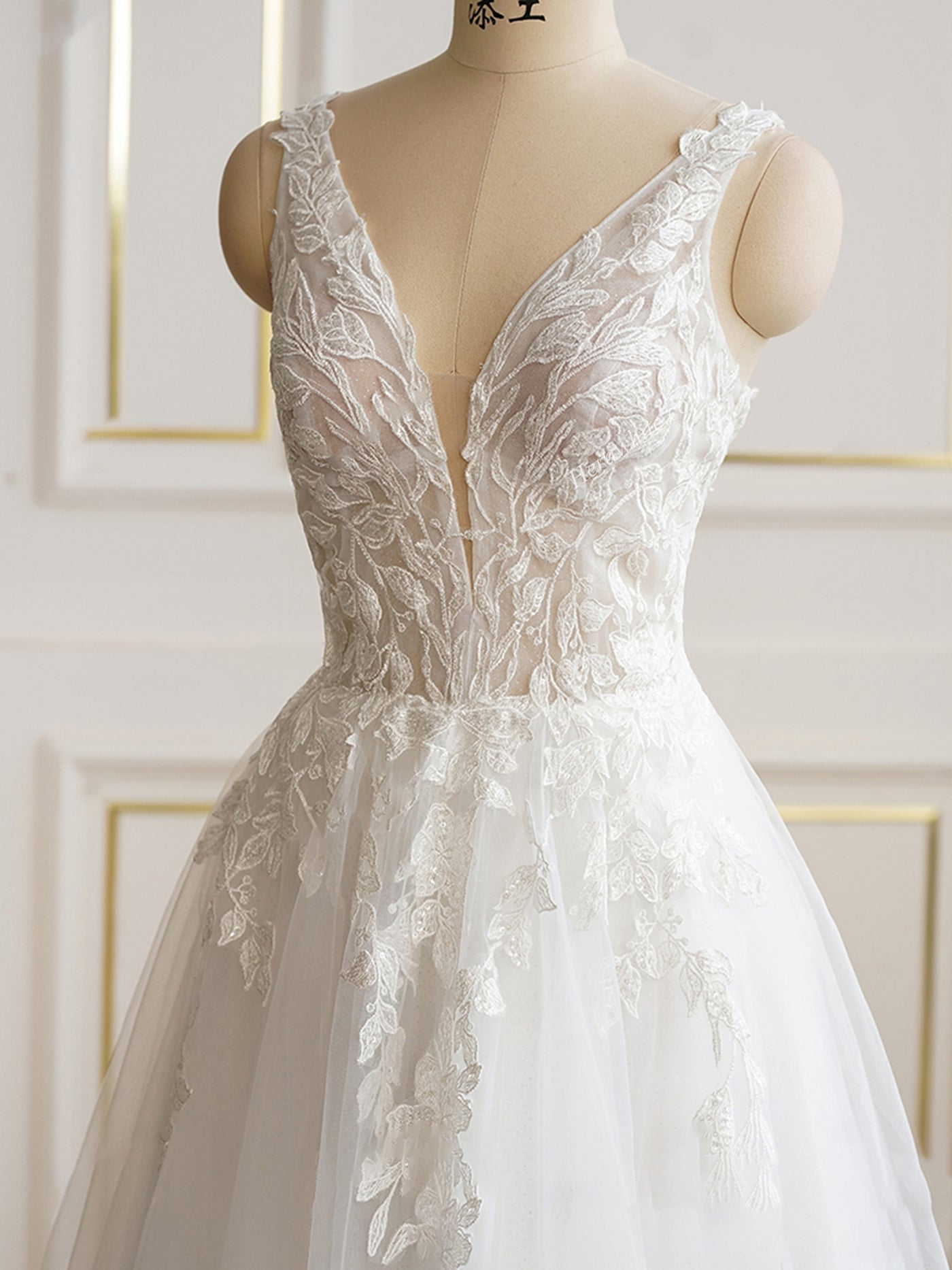 A Sexy Lace Plunging Neckline Sleeveless Bridal Gown on a Bergamot Bridal shop mannequin.