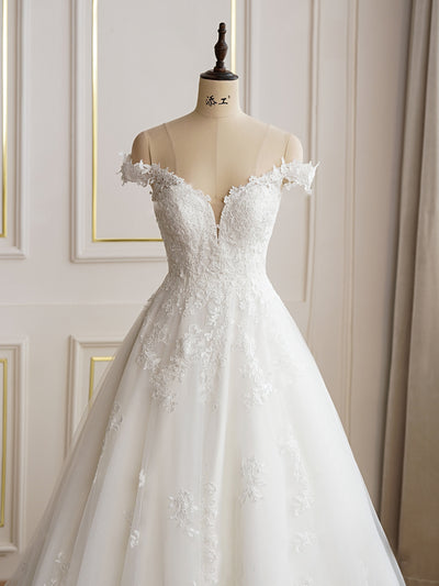 An Elegant Lace A-line Wedding Dress With Off the Shoulder Sleeves by Bergamot Bridal in a bridal shop.