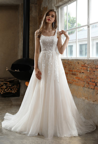 A woman in a (Square Neckline Wedding Dress with Delicate Leafy Lace) bridal dress standing in front of a fireplace.