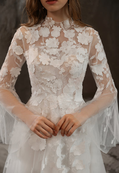 A bridal shop in London offers the Illusion High Neck Bridal Gown with Lovely 3D Floral Lace by Bergamot Bridal, a beautiful wedding dress with long sleeves.