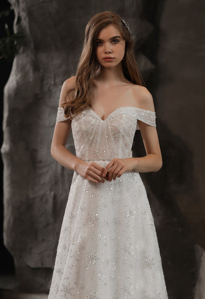 Off the shoulder wedding dress adorned with beading and lace, the Sparkly Beaded A-Line Bridal Gown With Off the Shoulder Sweetheart Neckline, available at Bergamot Bridal.