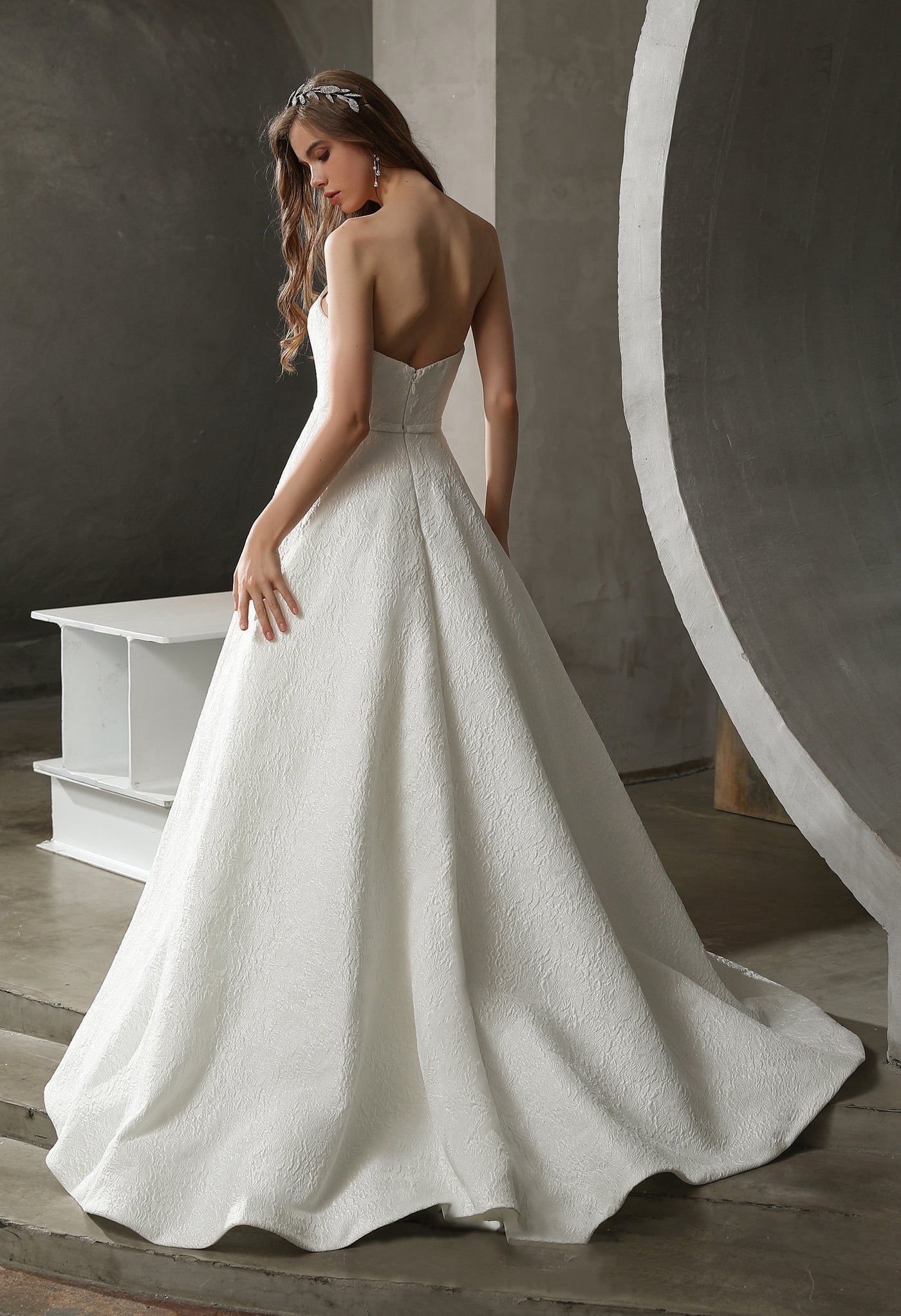 The back view of a woman in a Bergamot Bridal Strapless Ball Gown with Satin Jacquard and Detachable Puff Sleeves can be found at bridal shops in London.