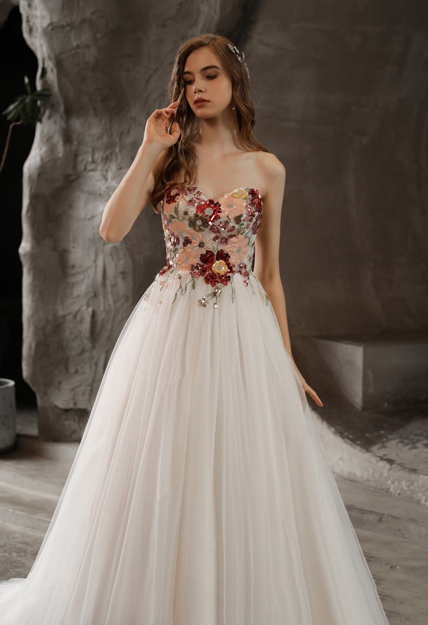 A woman in a Strapless Princess A-line Bridal Gown with Tulle Skirt and Floral Beaded Bodice from Bergamot Bridal, with flowers on it.