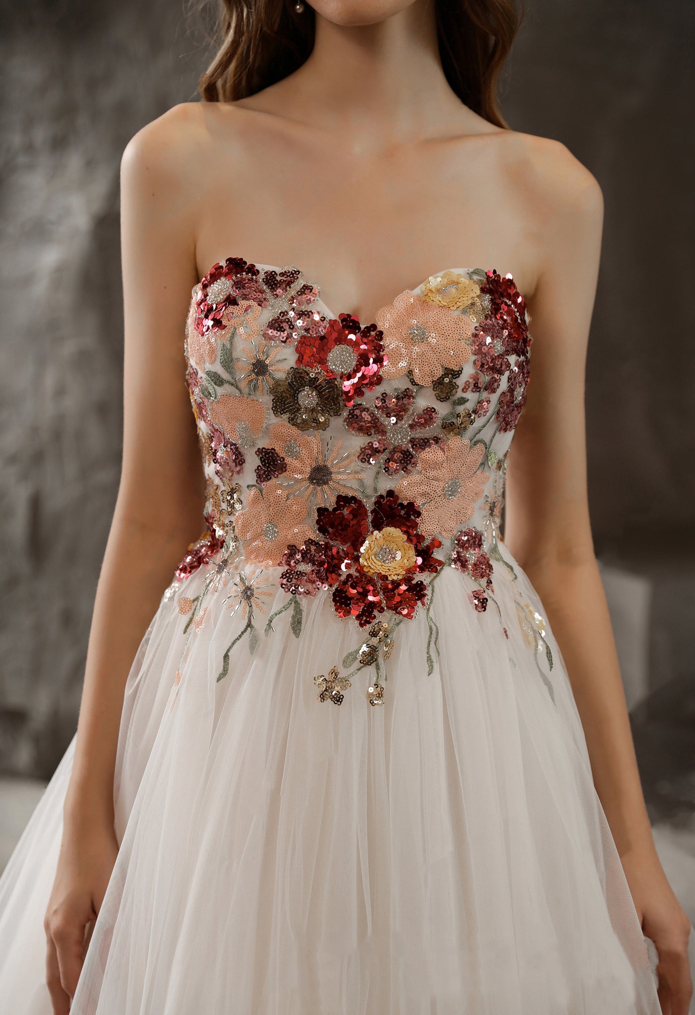 A woman in a wedding dress with flowers on it, shopping for her perfect Bergamot Bridal Strapless Princess A-line Bridal Gown with Tulle Skirt and Floral Beaded Bodice at a bridal shop in London.